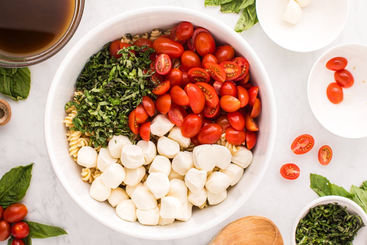 mozzarella, tomatoes and half of the basil ribbons added to bowl with pasta