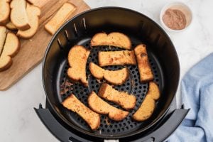 cooked french toast sticks in an air fryer basket