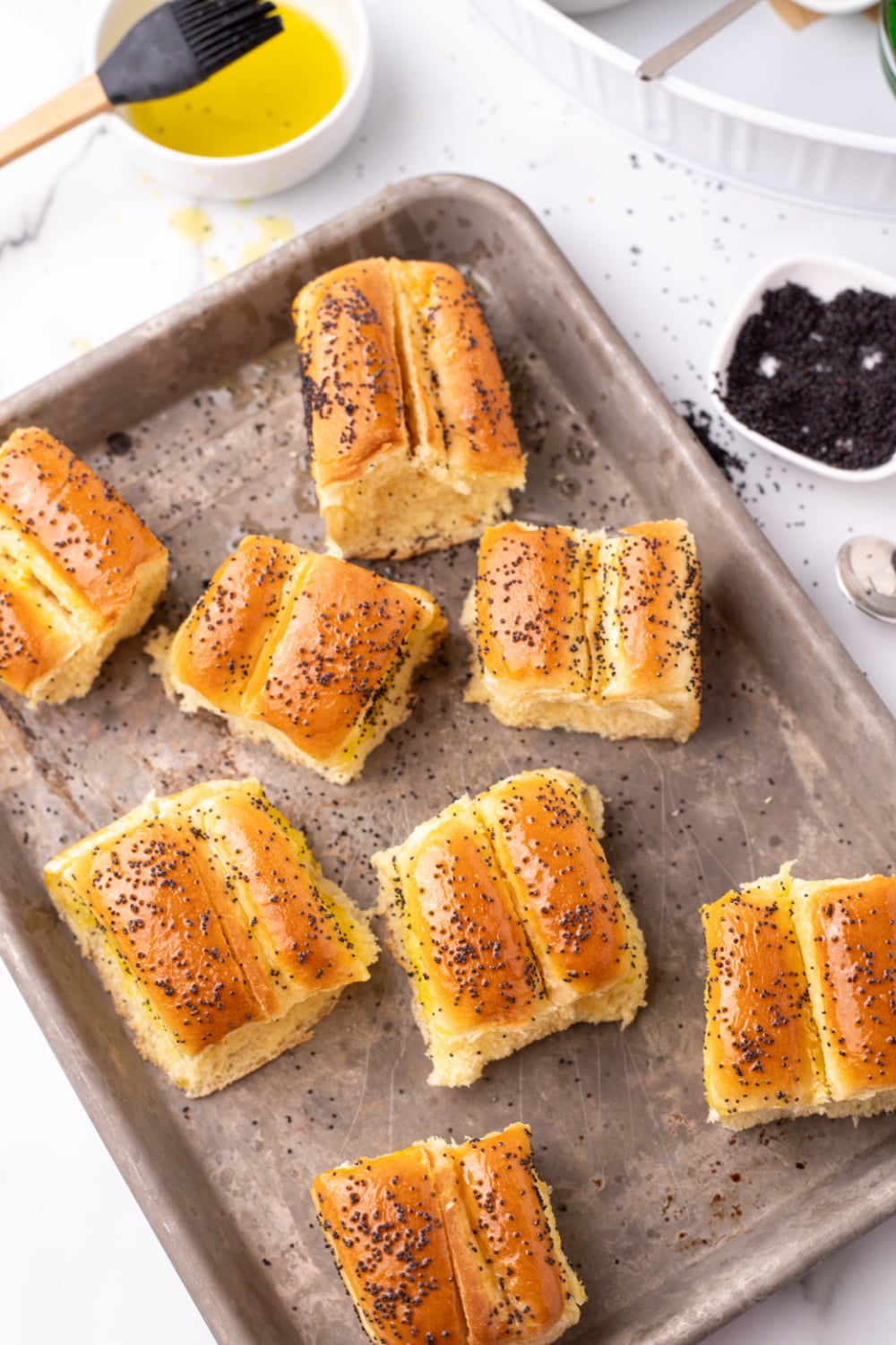 dinner rolls with poppy seeds on a baking sheet