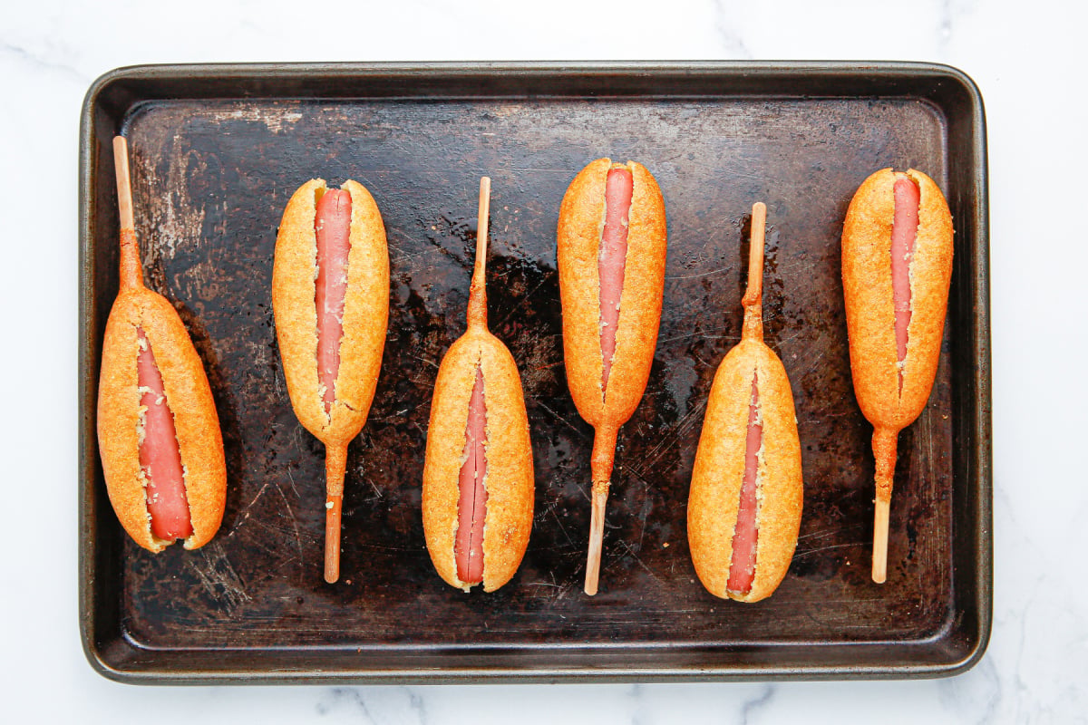 corn dogs slit lengthwise on baking sheet