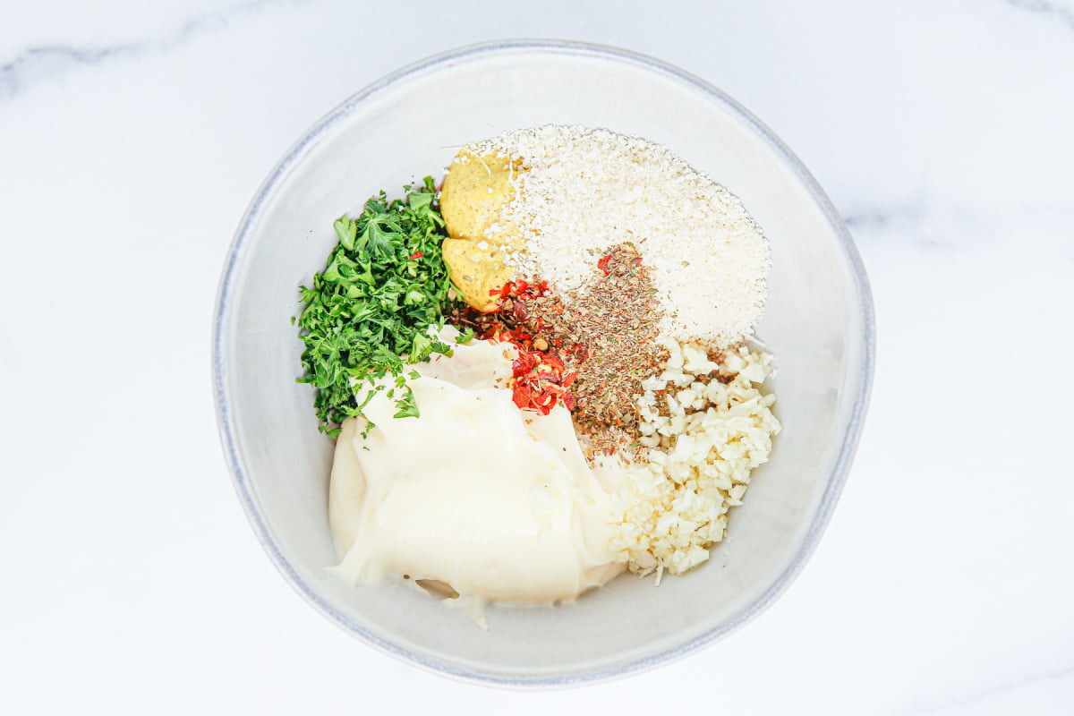 mayonnaise, minced garlic, parmesan cheese, fresh parsley, red wine vinegar, spicy mustard, oregano and red pepper flakes in a bowl