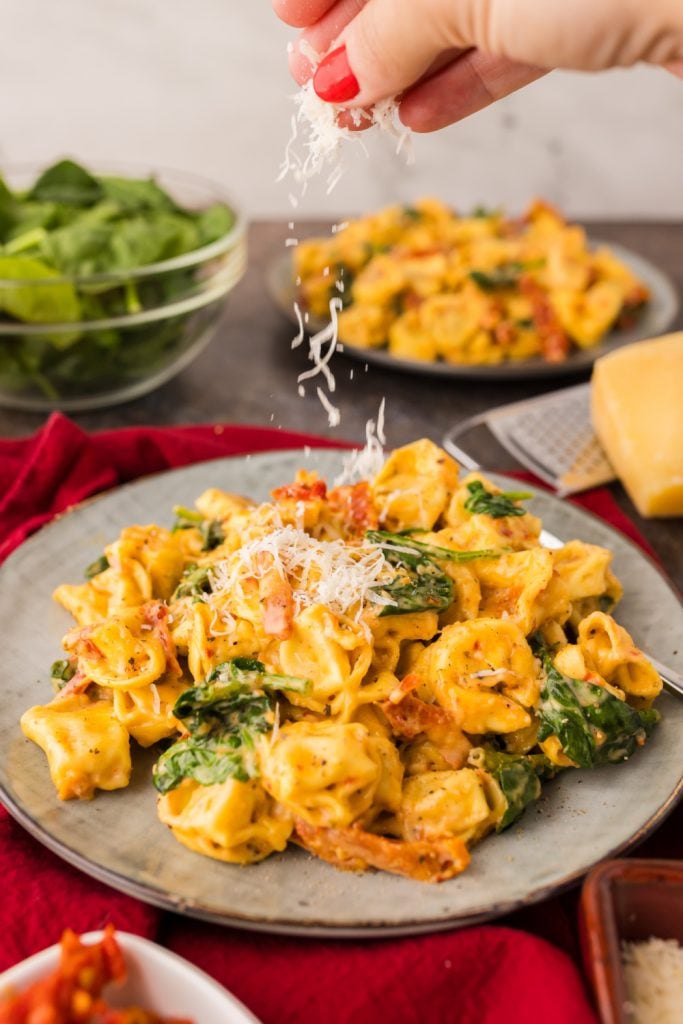 One Pan Marry Me Tortellini on a plate with cheese being added