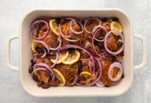 lemon slices, kalamata olives, and red onion added to baking dish with chicken