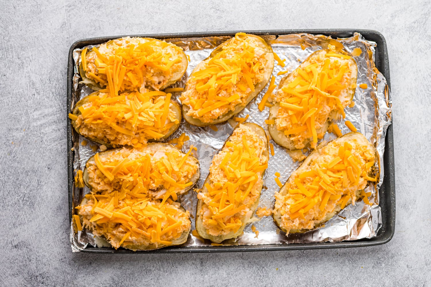 Buffalo chicken mixture placed in potato hallows and topped with cheese