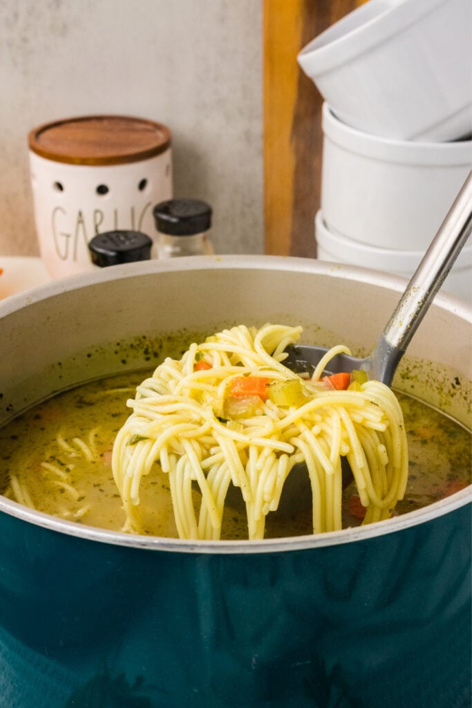 Classic Vegetable Noodle Soup in a pot wiht a laddle