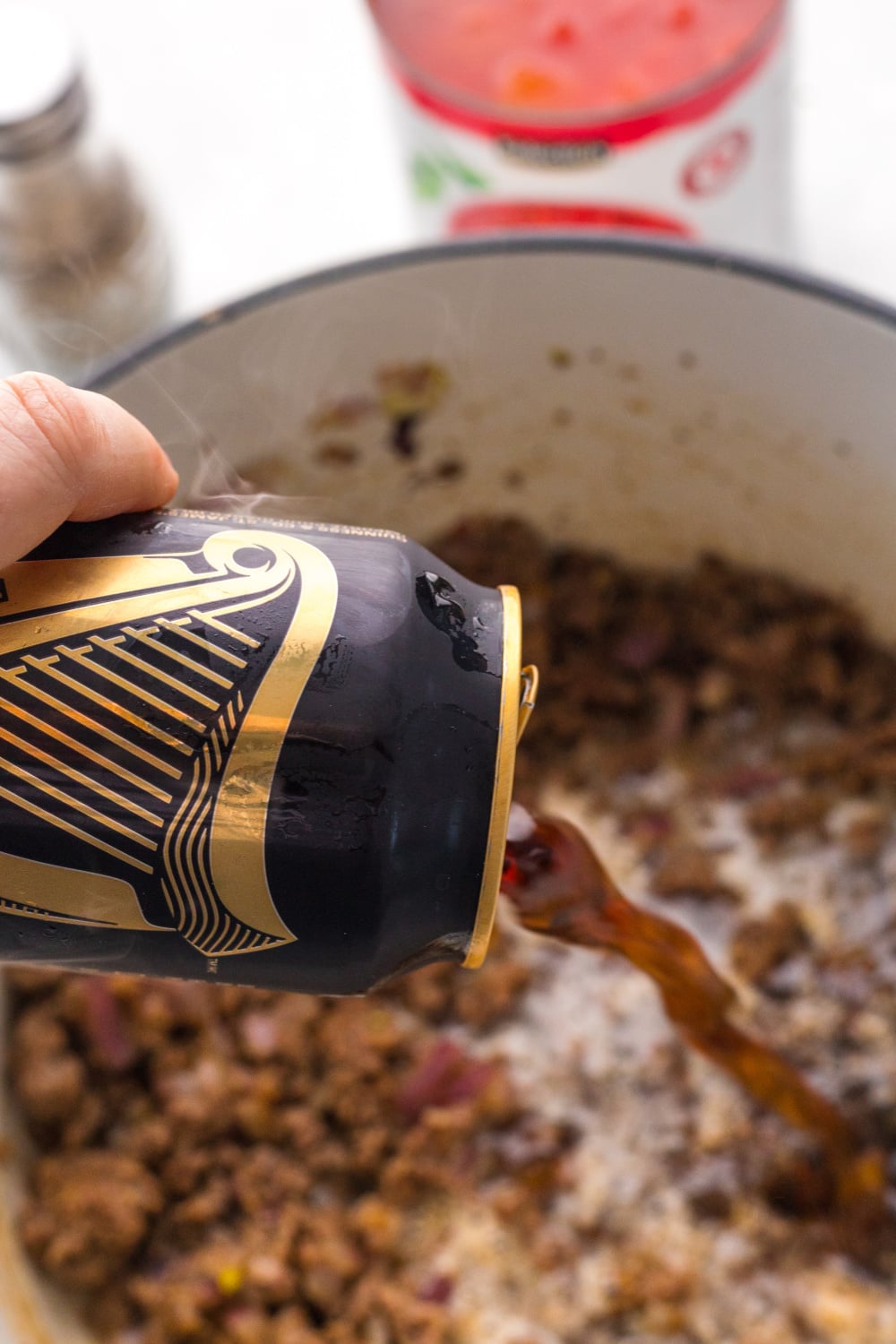pouring guinness into pot of chili